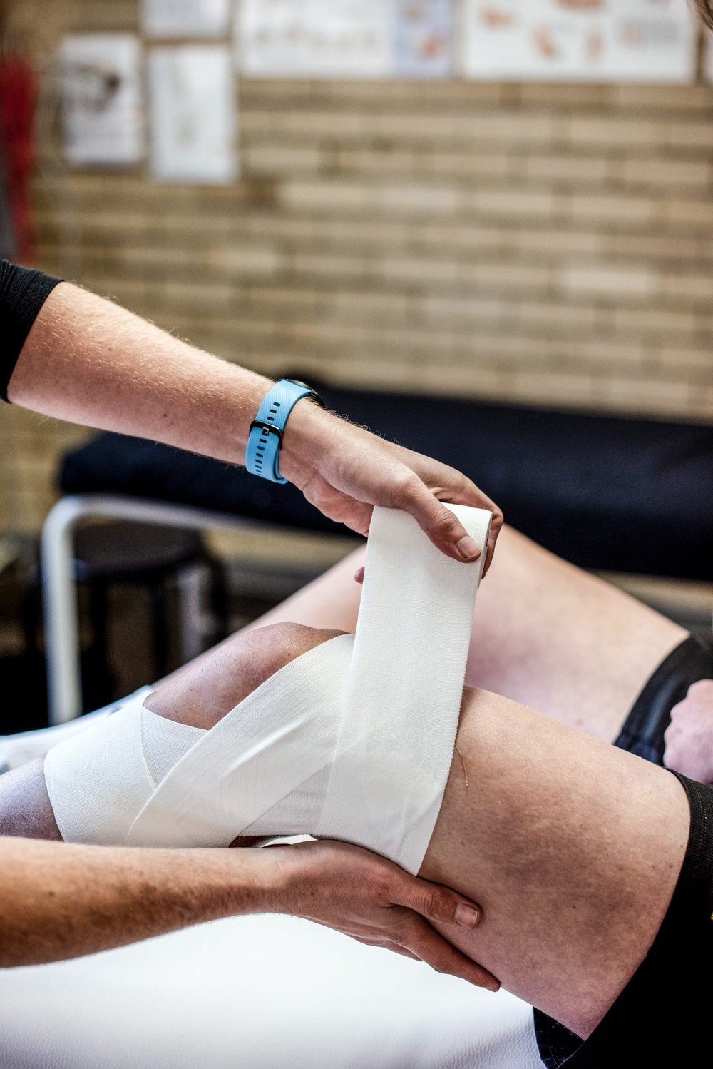 Elastic adhesive bandage being applied around a knee