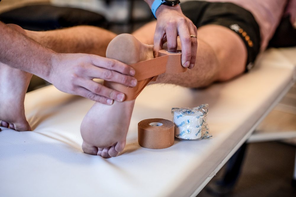 Rigid sports tape being applied around an athlete's ankle